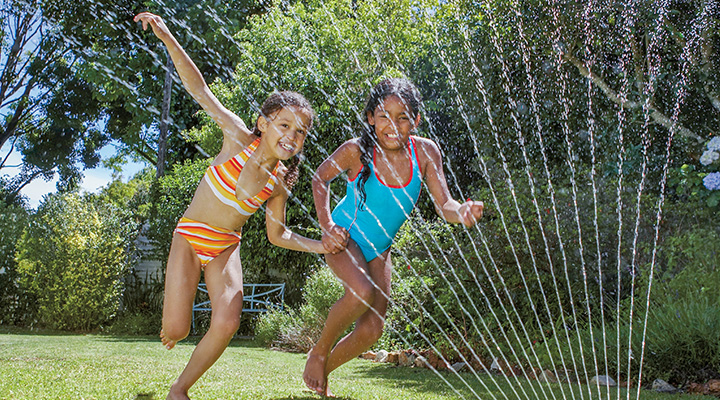 Photo of two kids playing in the sprinkler